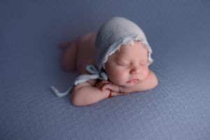 Newborn baby laying on tummy leaning head on hands