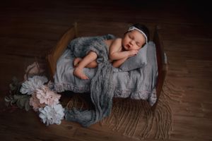 Newborn baby laying on baby prop bed for newborn photography shoot