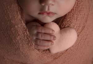 close up of Newborn baby holding felt heart prop in Beaverton Oregon studio