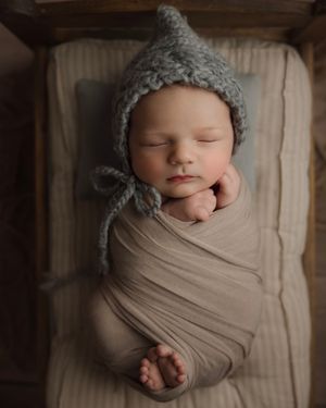 newborn baby in tiny bed prop