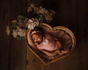 newborn baby swaddled in basket shaped as heart in Portland Oregon studio
