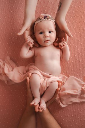 Older baby holding parents hands for photoshoot in studio