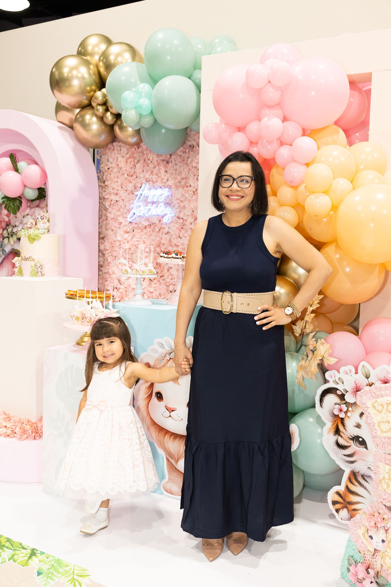 Festive birthday party setup with pastel balloon garland and decorative backdrop.