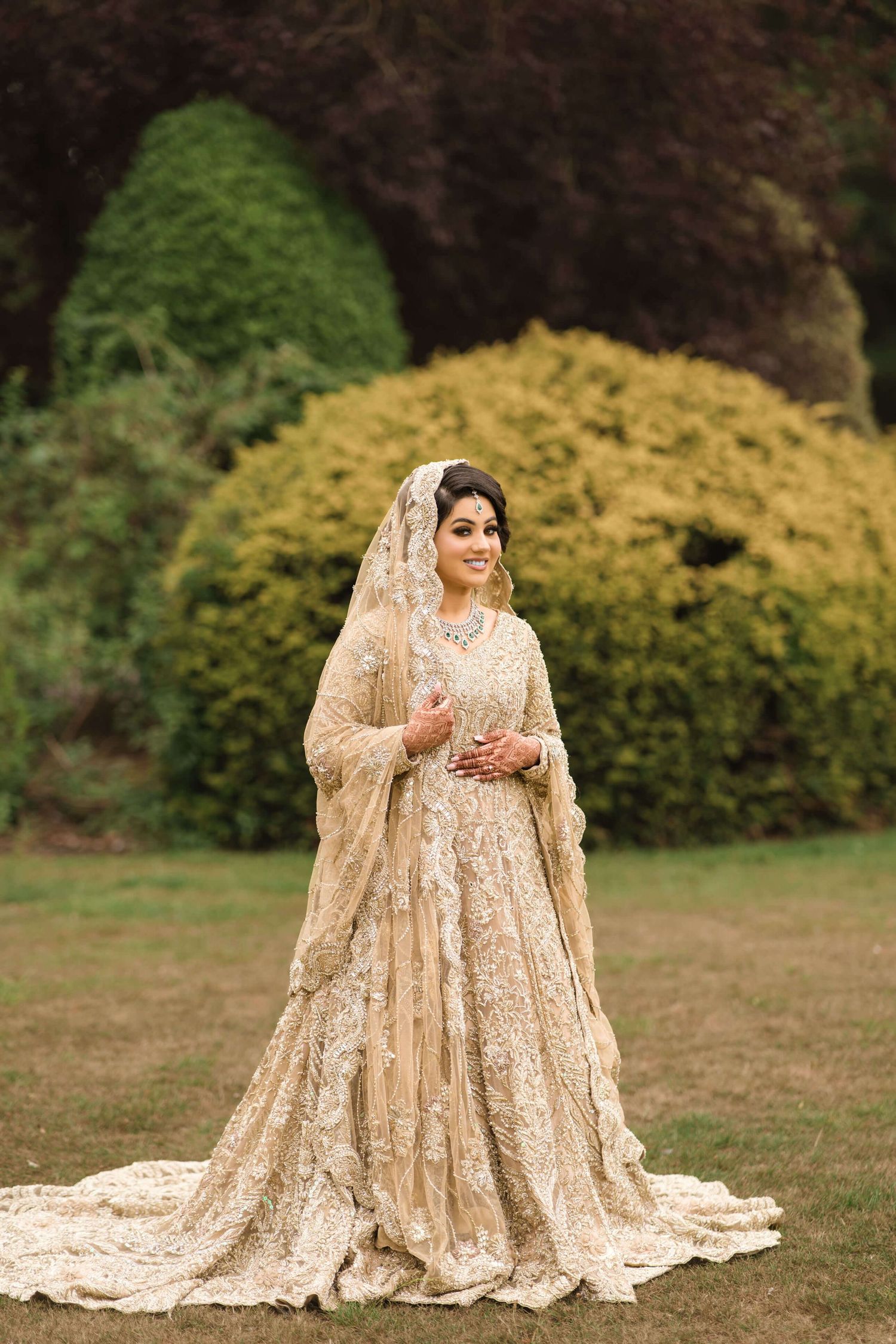 newly wedded wife posing after holy matrimony smiling blissfully towards the camera, wearing a golden Lehenga