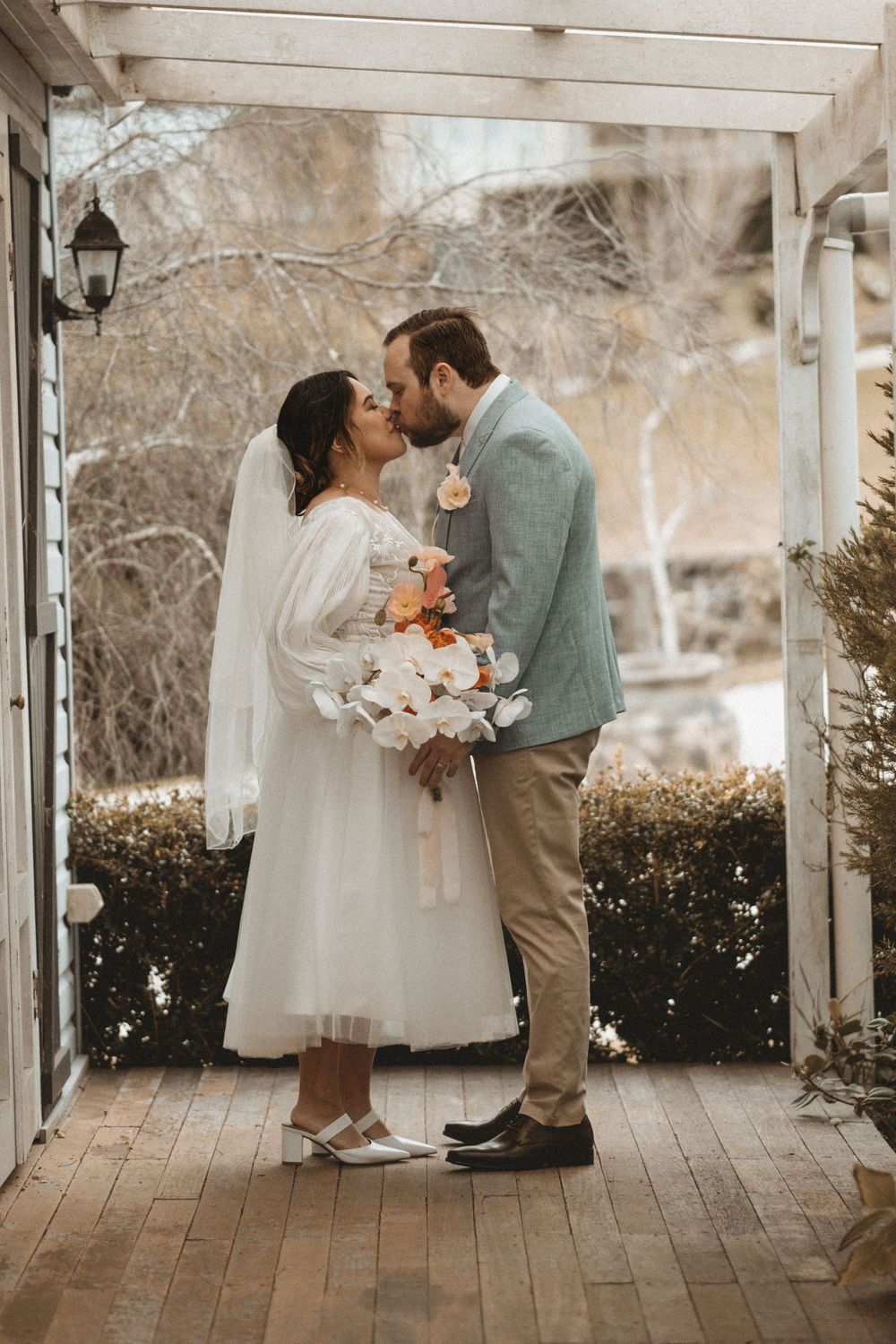 Wedding couple sharing a romantic moment under a white pergola during their ceremony.