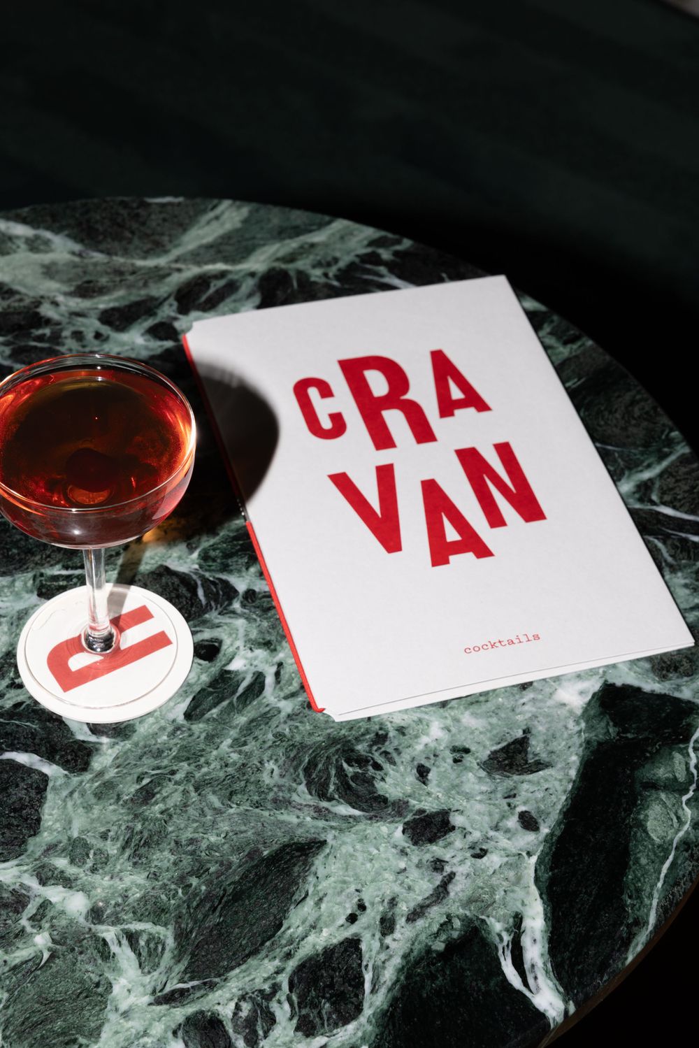 Wine glass and menu with 'CRAVAN' text on dark marble surface.