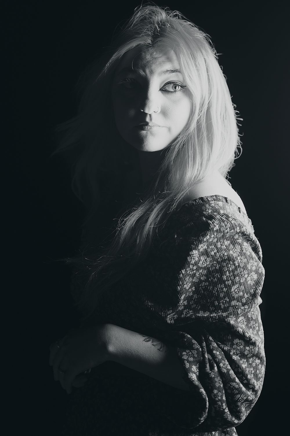 Dramatic black and white portrait with moody lighting highlighting delicate features.