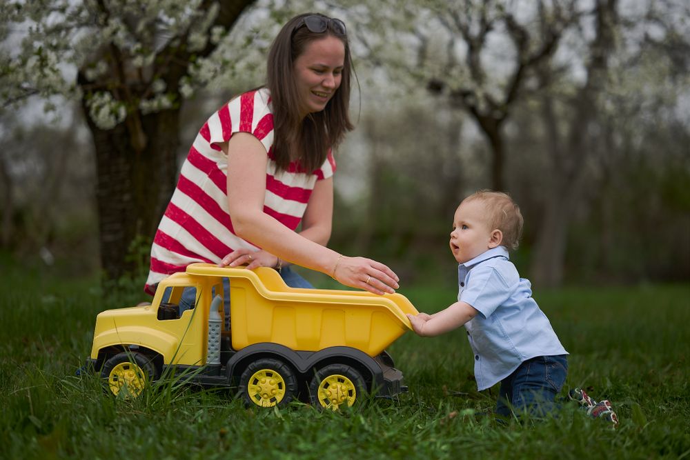 Playtime with a yellow toy dump truck in a spring garden.