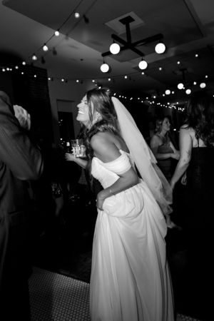 A bride dances at her wedding reception under twinkling lights and globe lanterns.