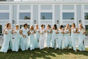 Bridesmaids in matching light blue dresses pose together on a lawn.