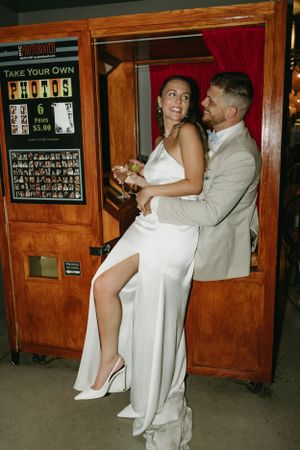 A couple shares an intimate dance moment in front of a wooden photo booth at a wedding reception.