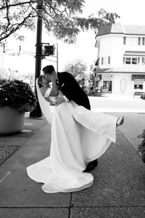 A classic black and white wedding photo captures a romantic dip pose on a city street.