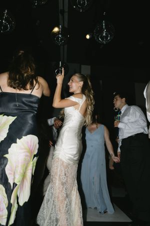 Wedding reception dance party with guests in formal attire under crystal chandeliers.