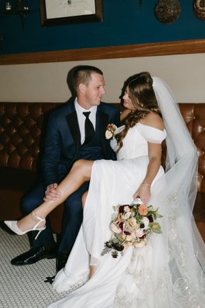 Intimate wedding portrait of couple sitting together on vintage leather seating.