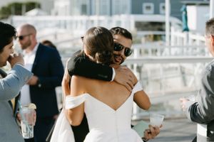 Wedding guests share warm embraces during an outdoor reception celebration.