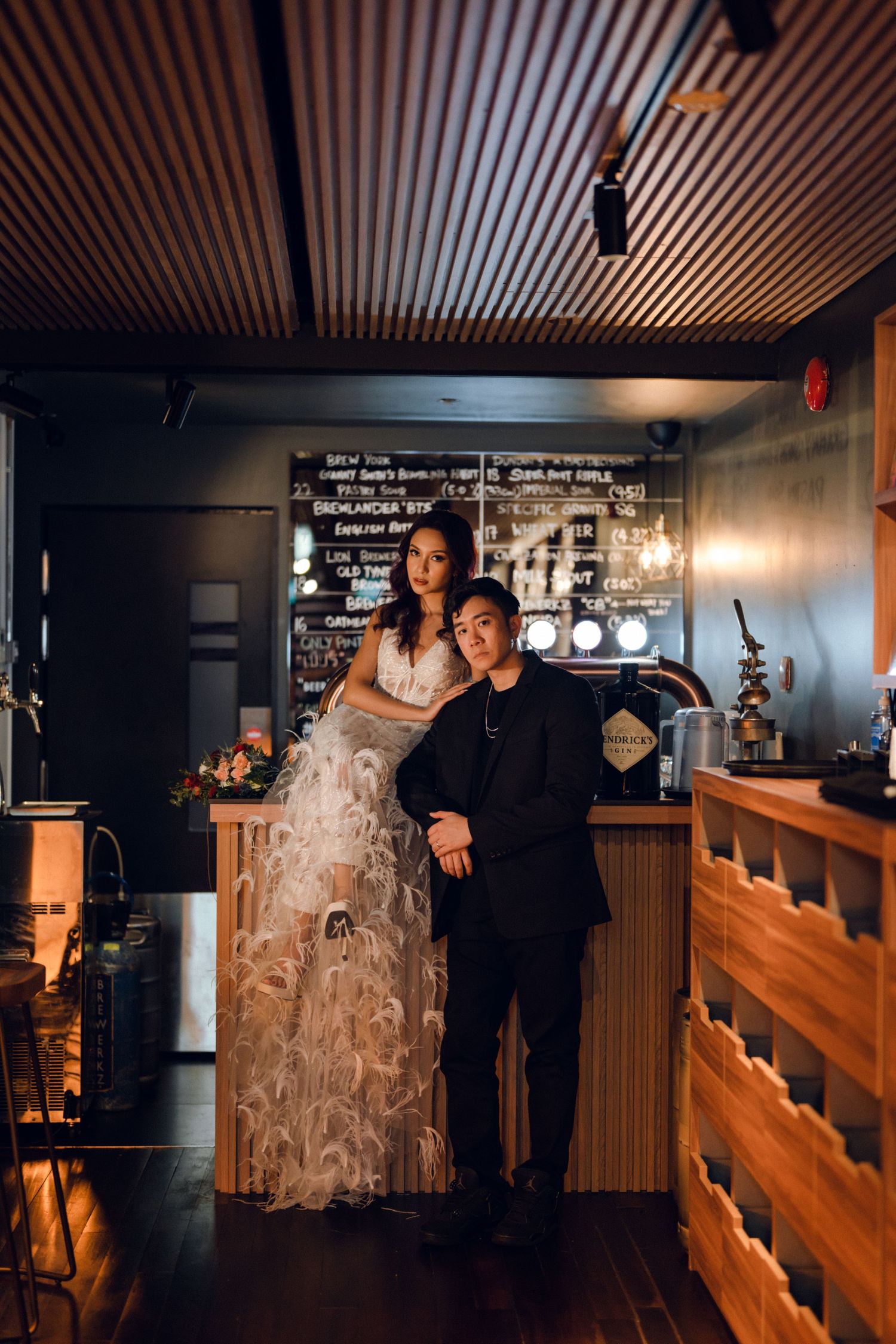 A couple poses together in a dimly lit restaurant with wooden paneling and warm lighting.