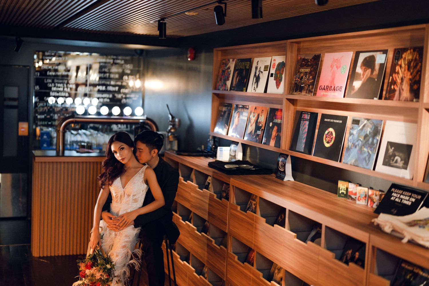 Wide angle view of a modern restaurant interior with wood paneling and display shelves.