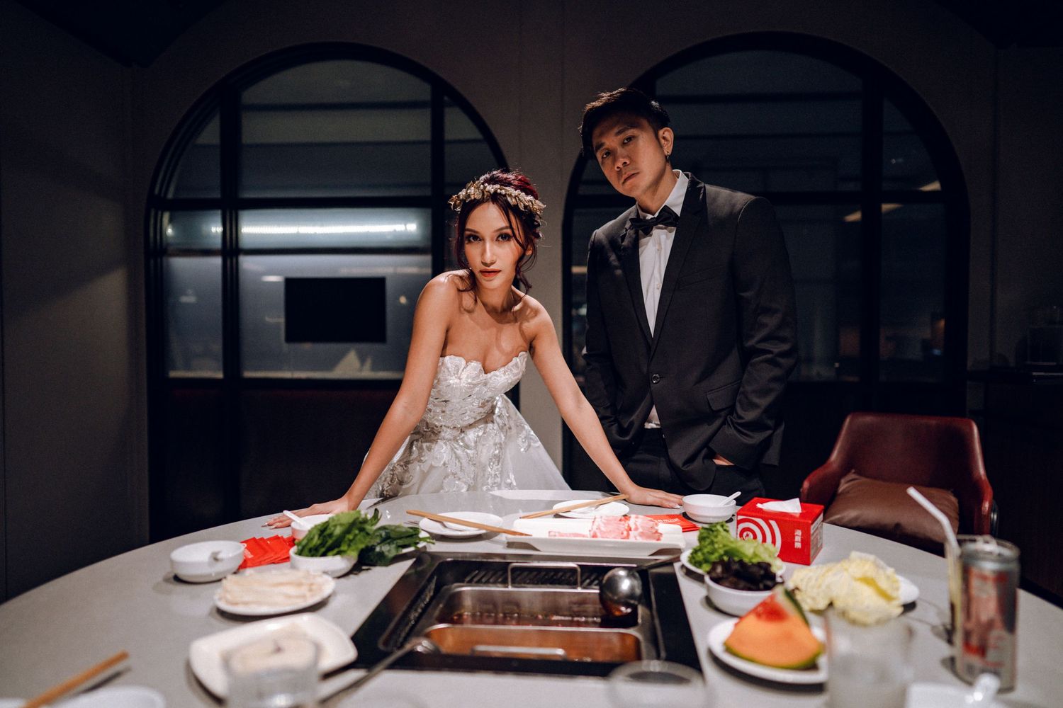 Couple enjoying an intimate dinner at a dimly lit restaurant with elegant table settings and mood lighting.