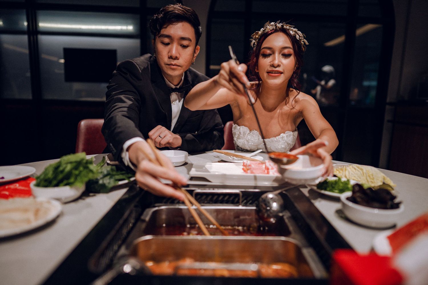 Elegant dining setup with traditional hot pot and fresh ingredients on white tablecloth.
