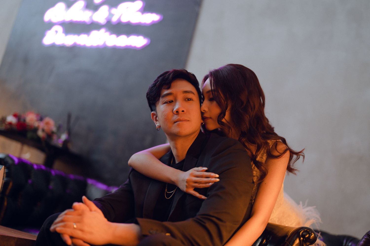 Intimate moment between couple on couch with purple neon lighting.