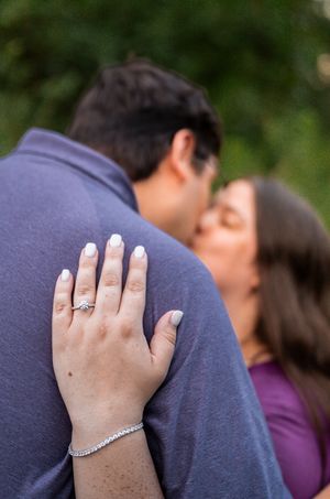 A close-up series showing hands with an engagement ring embracing against a navy blue shirt and purple top.
