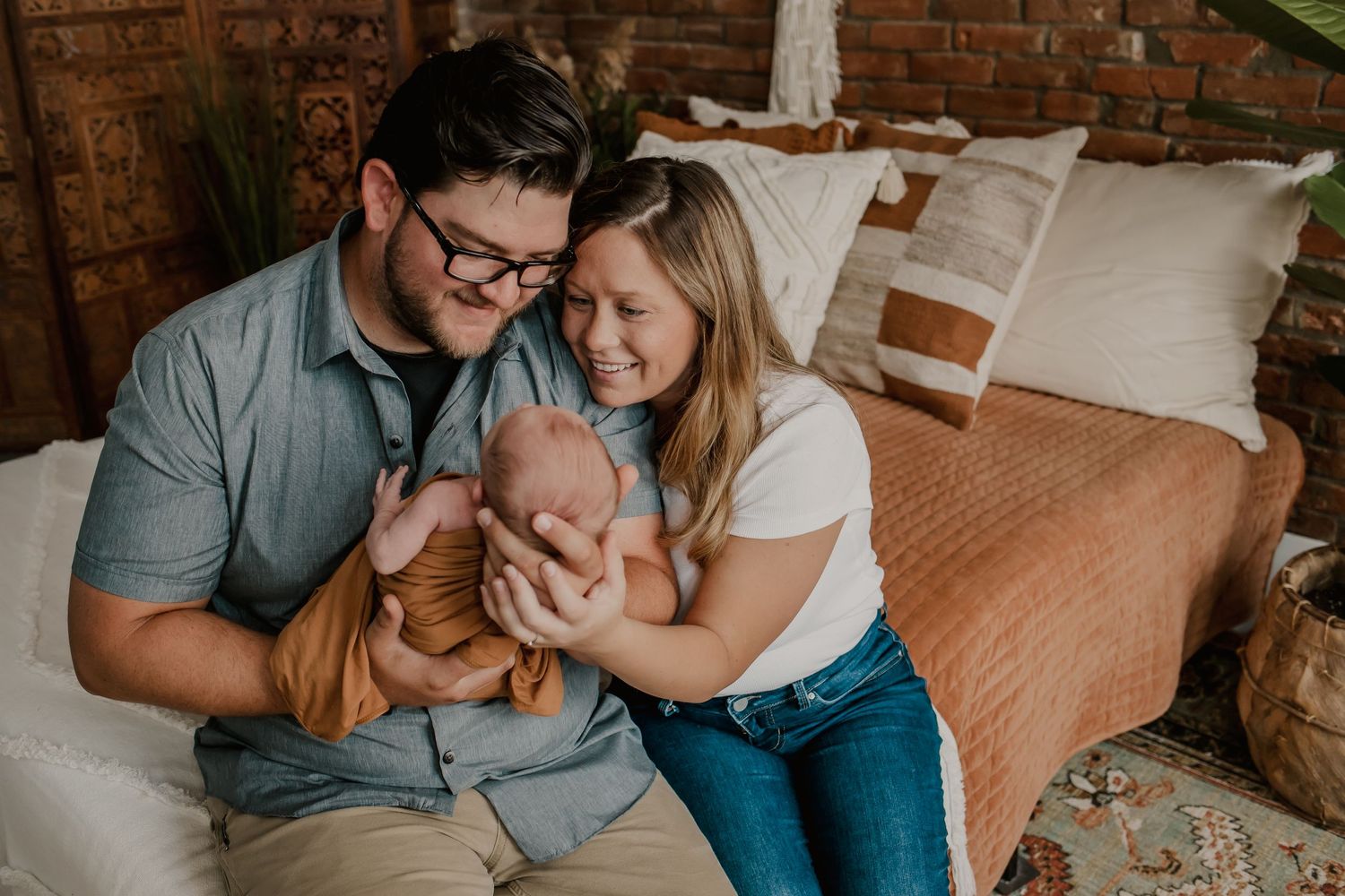Mom and Dad holding their newborn baby in a beautiful boho photography studio with Fully Known Services.