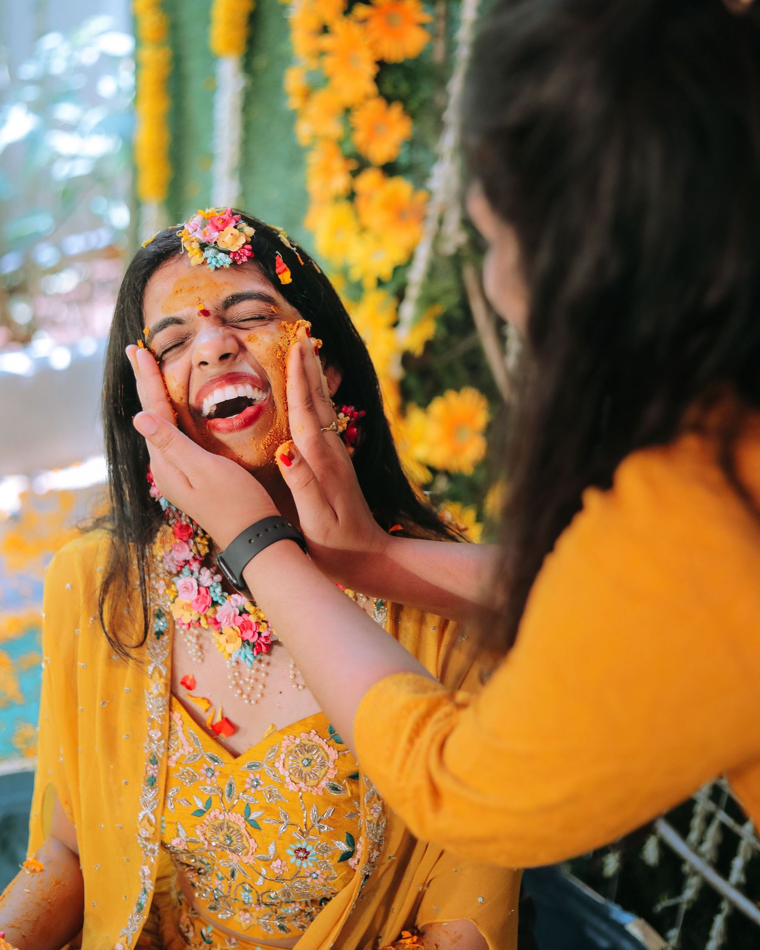 Joyful moment during Haldi ceremony with yellow and orange marigold decorations.