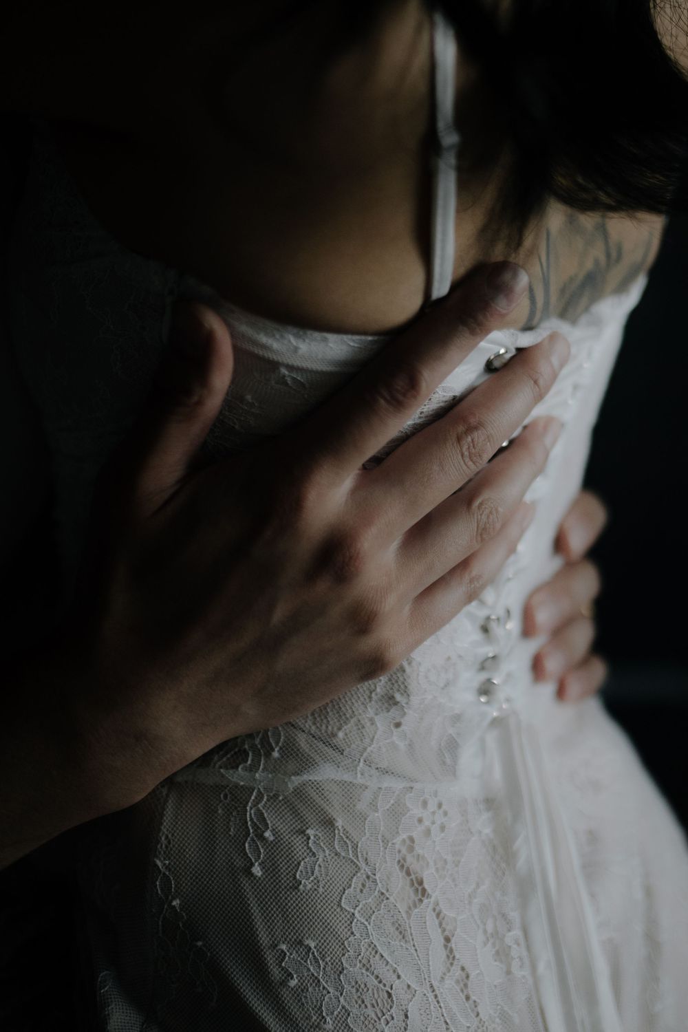Detailed shots of hands touching delicate white lace fabric in dark atmospheric lighting.