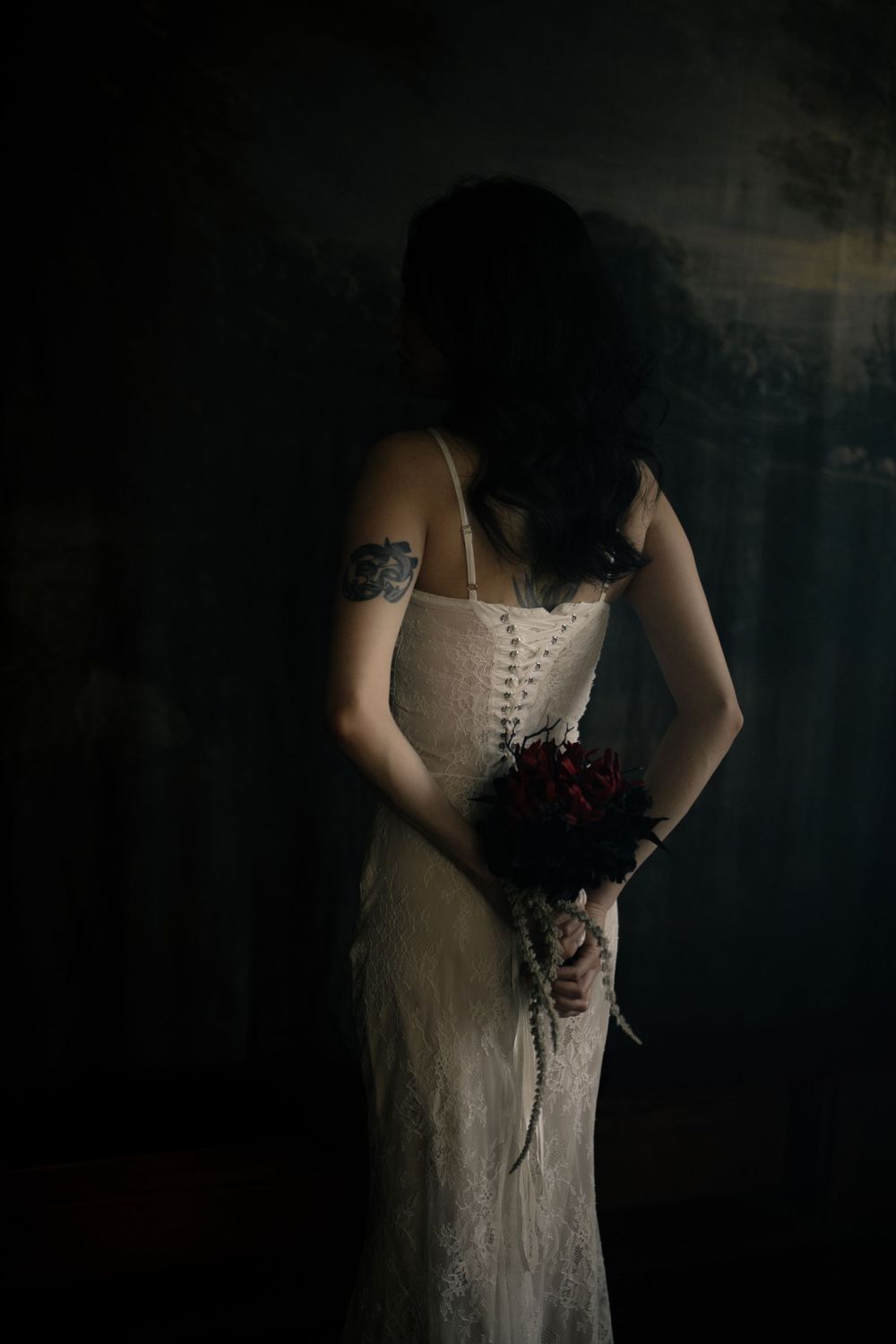 Detail shots of white corset dress against dark background in moody lighting.