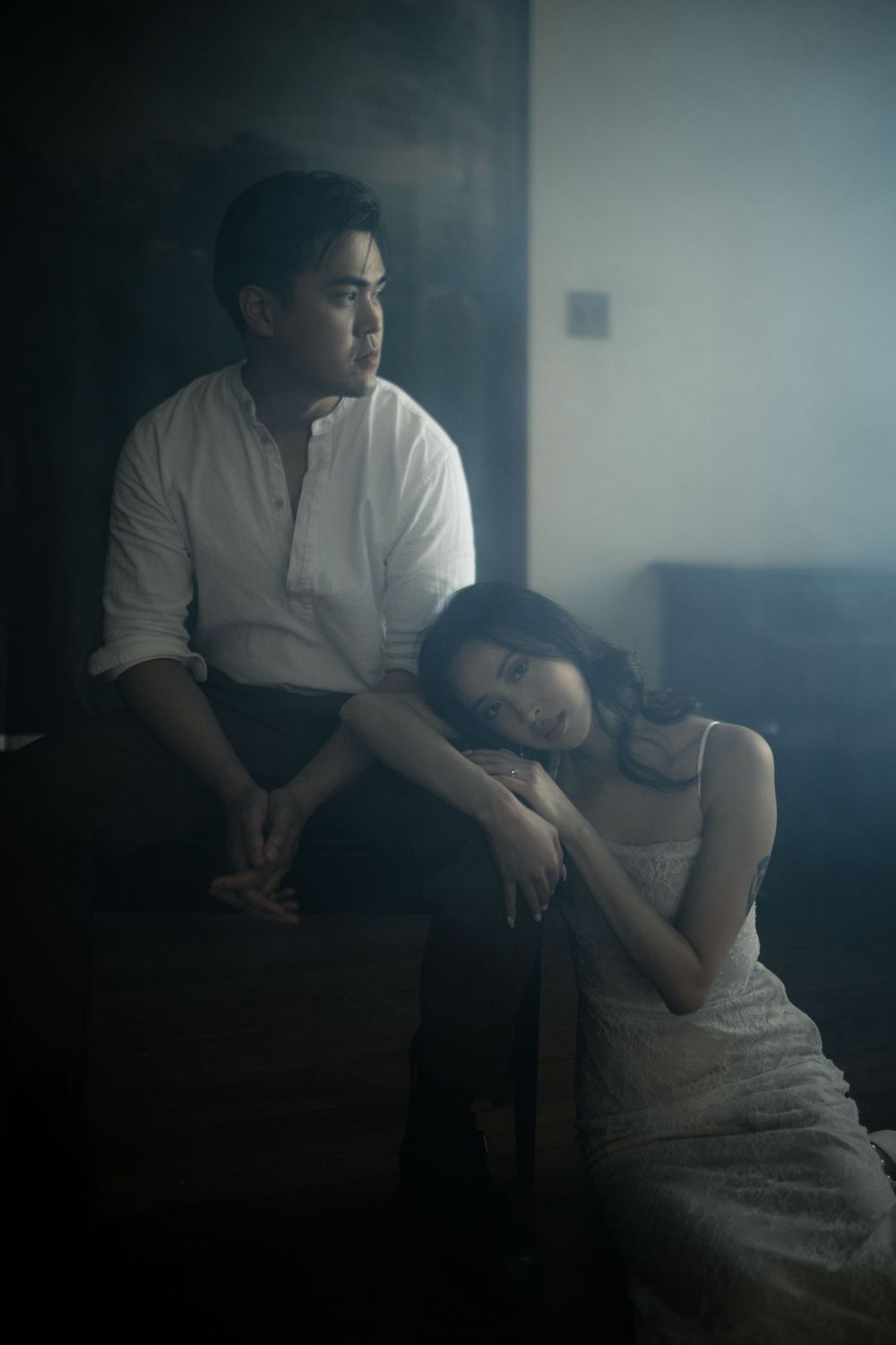 Atmospheric scene with figures sitting in misty, blue-toned lighting.
