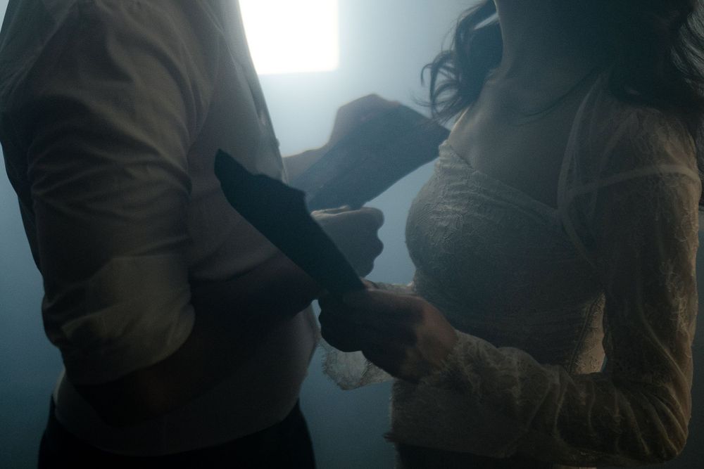 A backlit romantic scene shows two figures in shadow against bright window light.