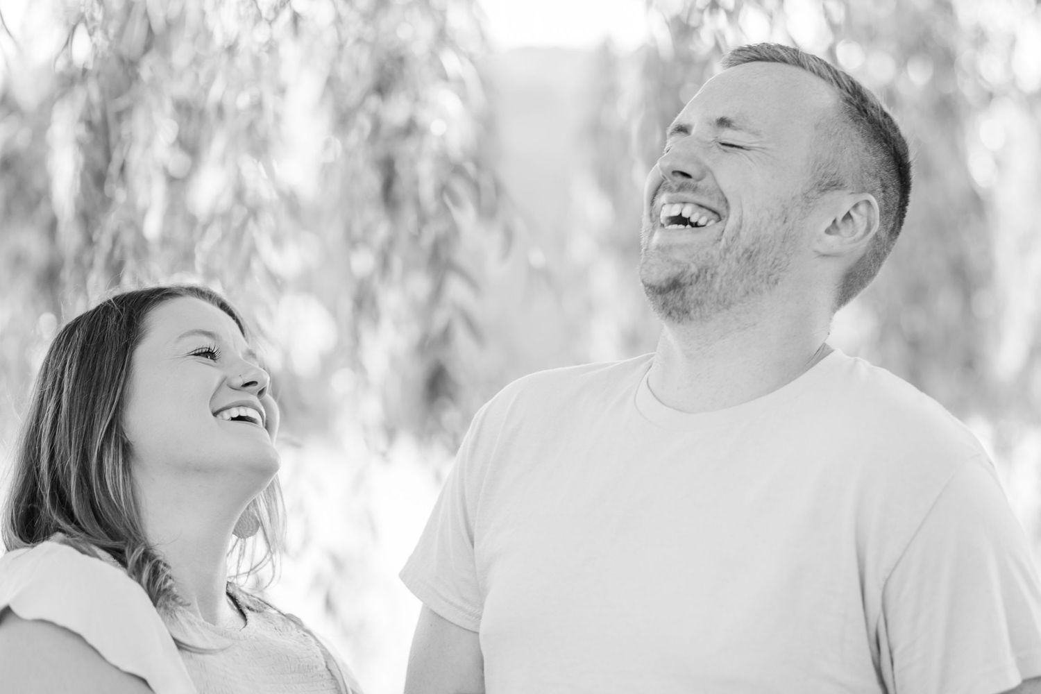 Joyful laughter captured in black and white under willow branches.