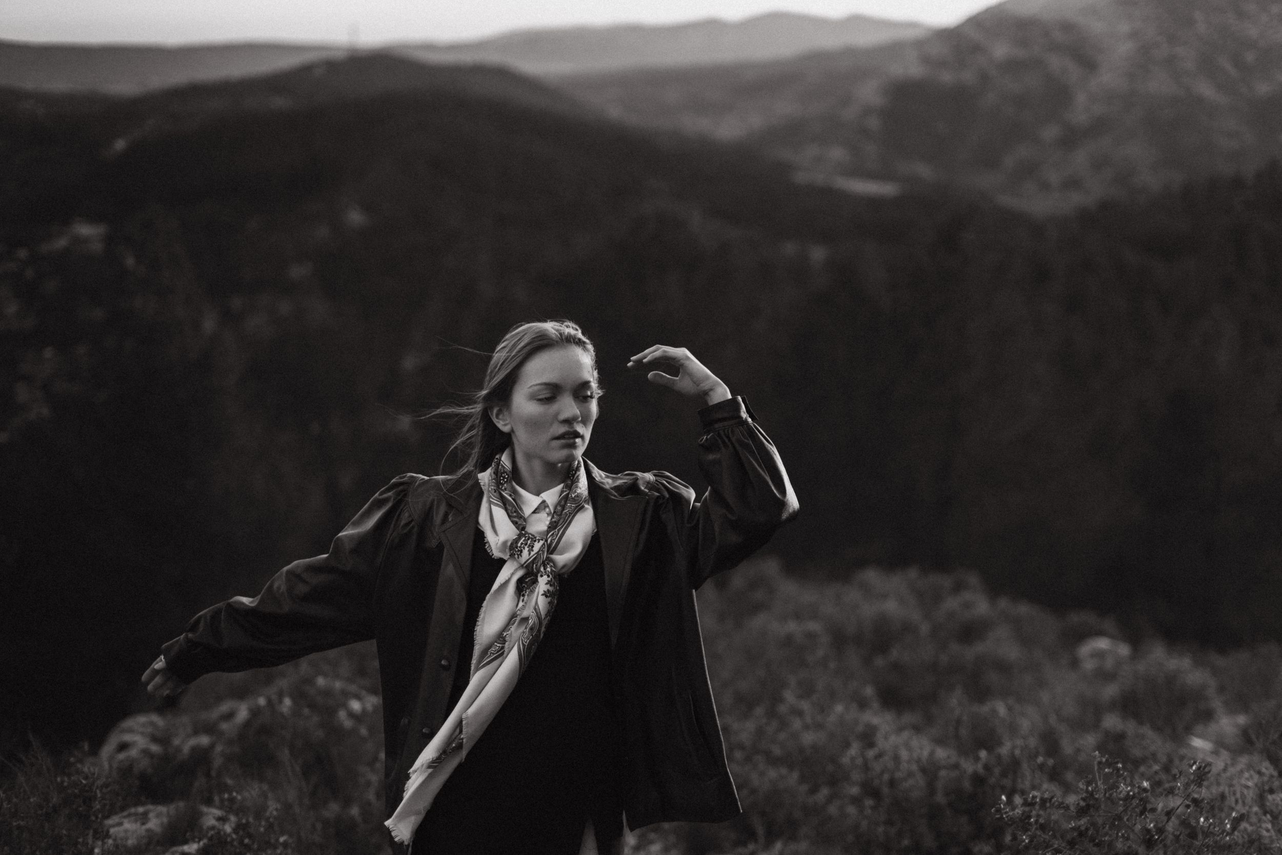 Black and white action shot of person in motion against mountain landscape.