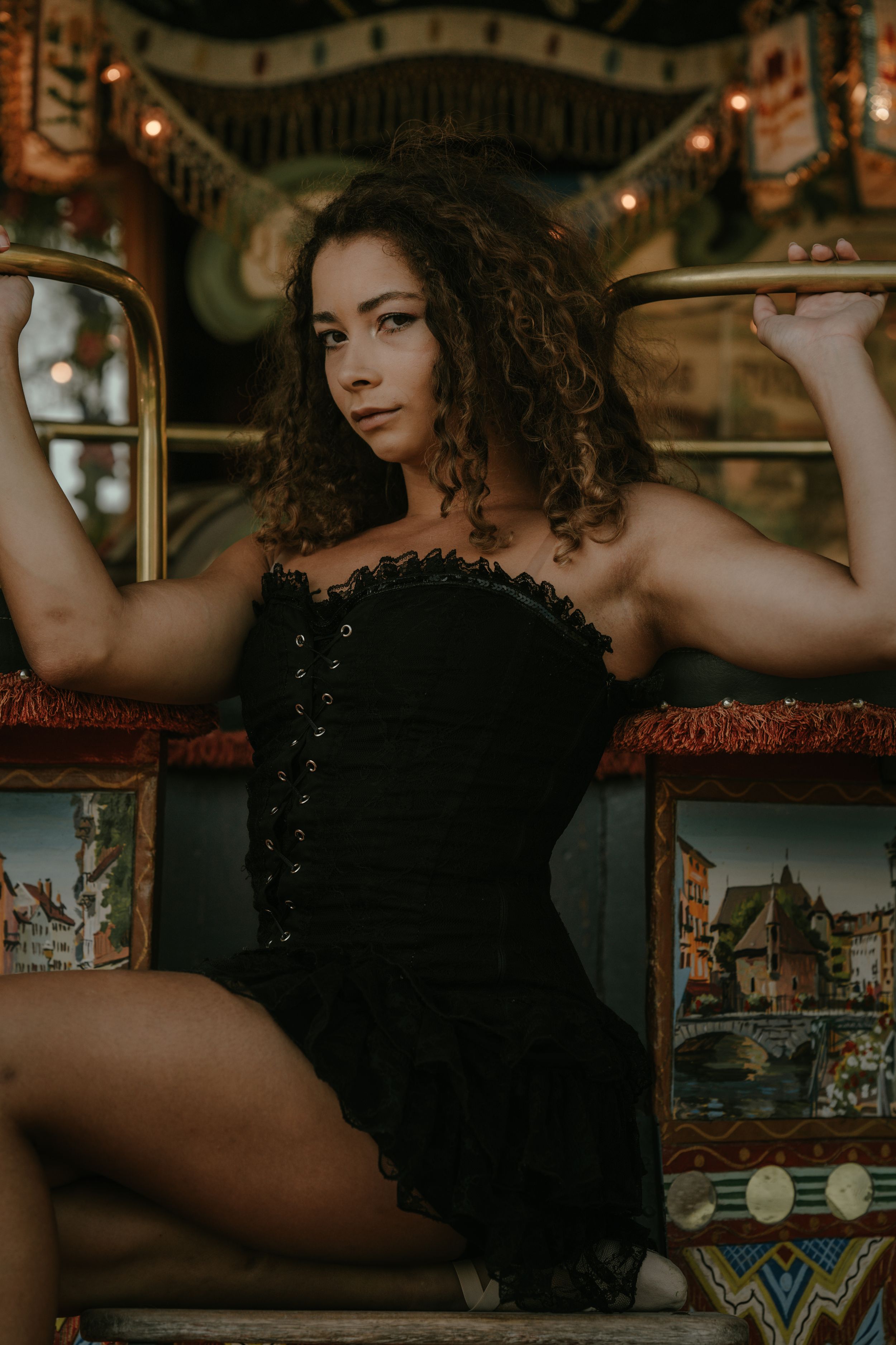 Dramatic portrait on carousel featuring black corset and curly hair.