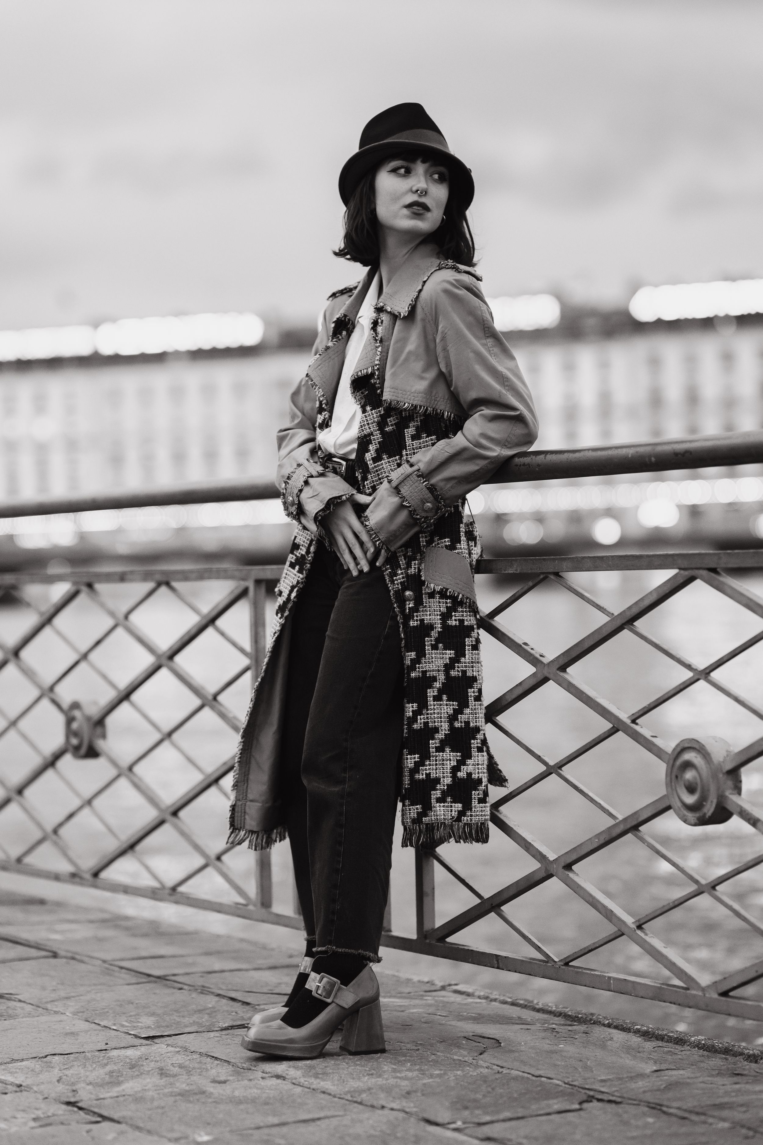Vintage-style portrait on bridge wearing hat and patterned coat.
