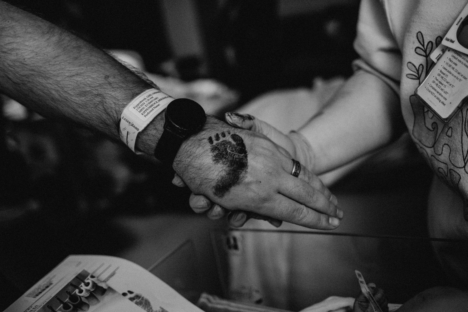 Birth photography by Fully Known Services.  Baby's footprint on Dad's hand.