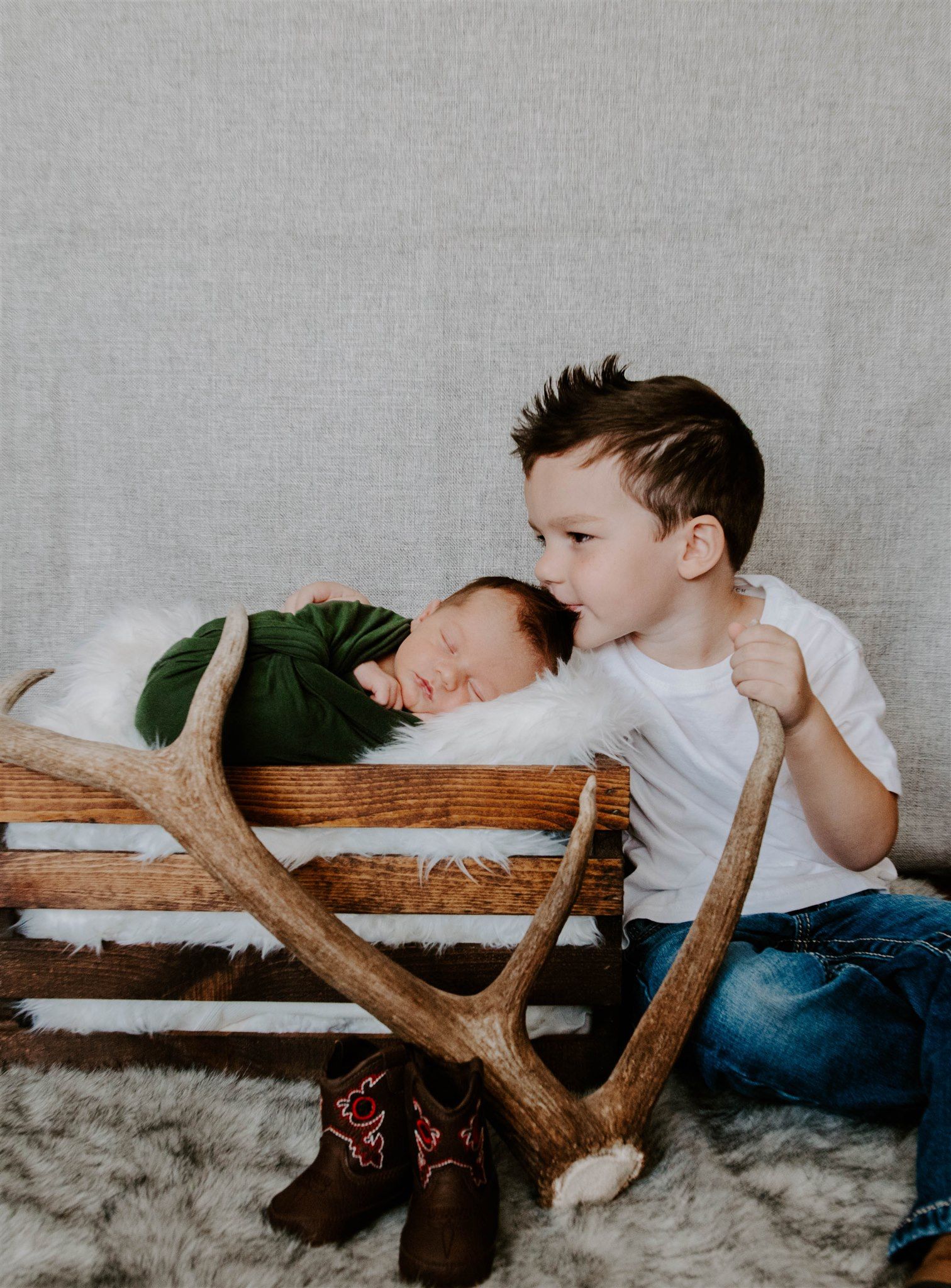 Children interacting with rustic wooden decor against gray background.