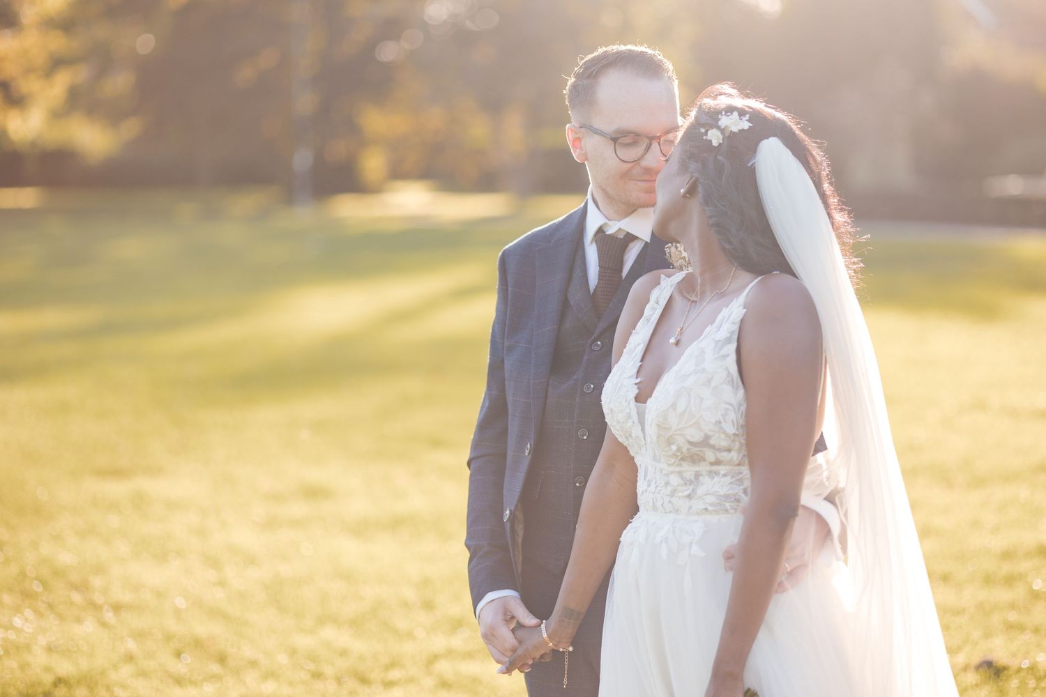 A romantic sunset wedding portrait shows the couple sharing an intimate moment in golden light.