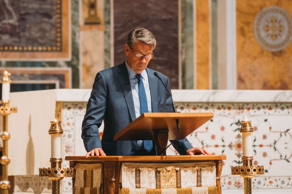 Religious official reading from a podium during a formal church ceremony.