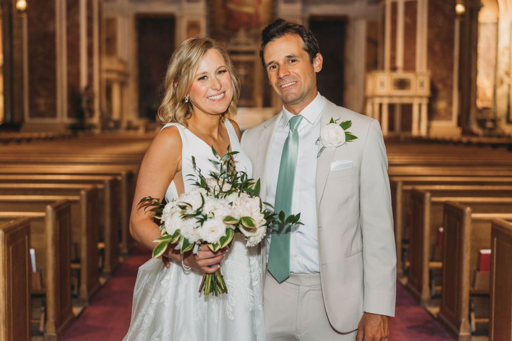 Wedding couple standing together in formal attire inside an ornate church setting.