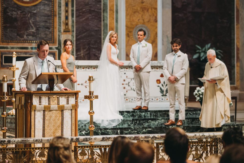 Wedding ceremony taking place at the altar of an ornately decorated Catholic church.