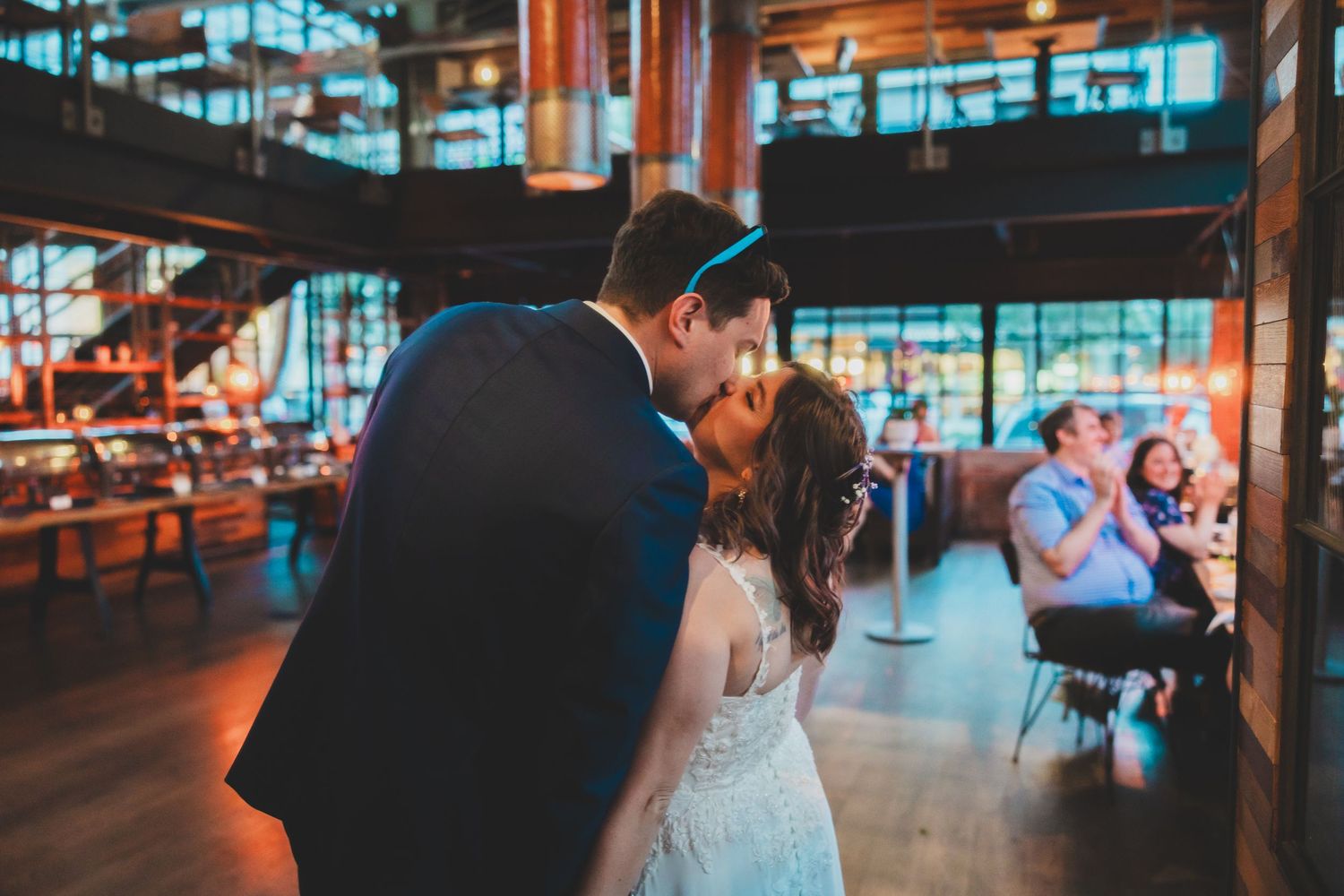 Wedding couple sharing intimate moment on dance floor with industrial venue setting.