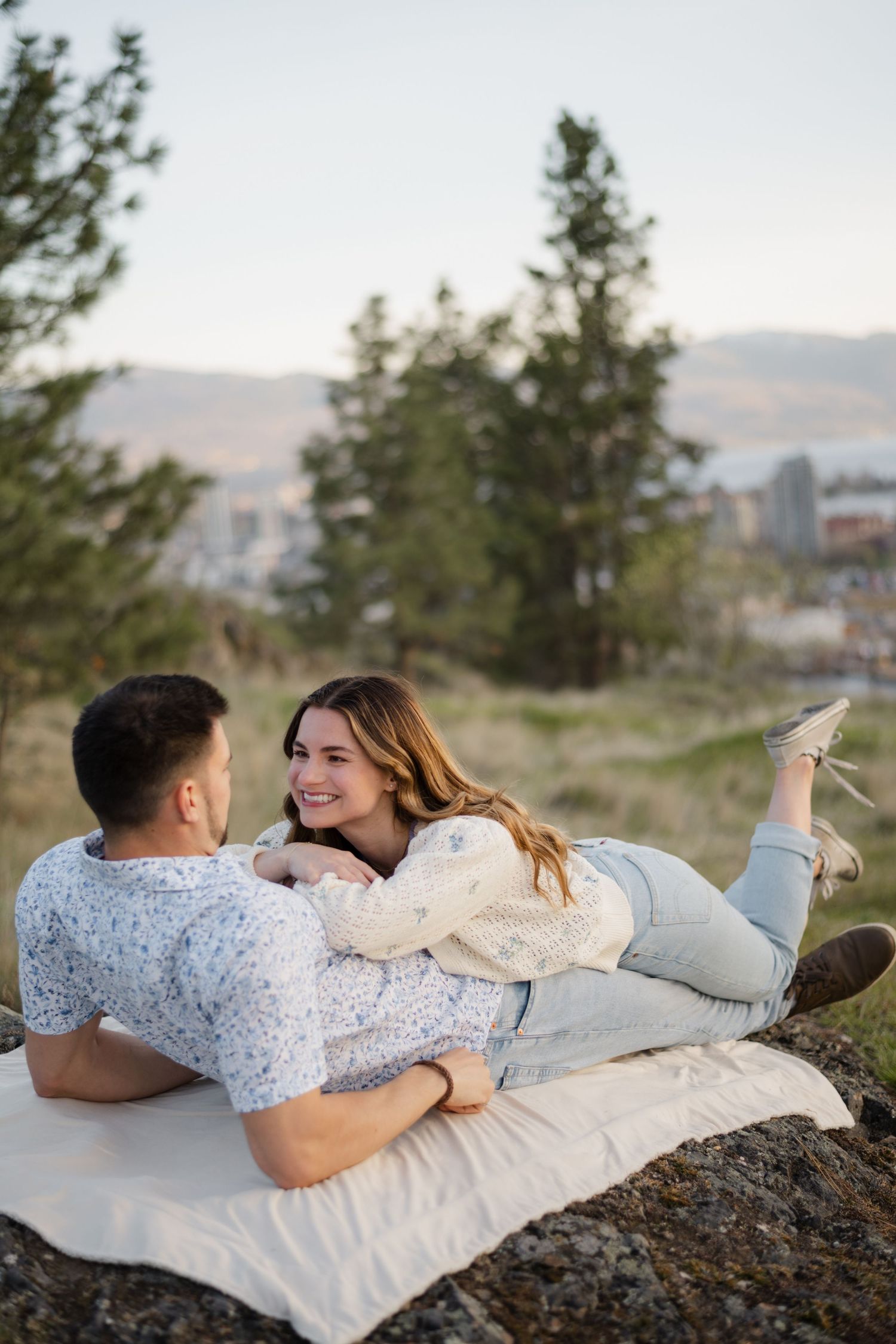 couple laying down on a mountain in a field
