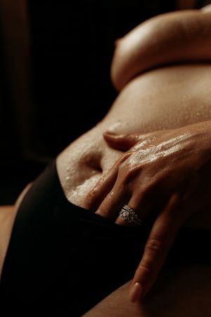 Close-up intimate portrait showing hand with ring against skin in moody lighting.