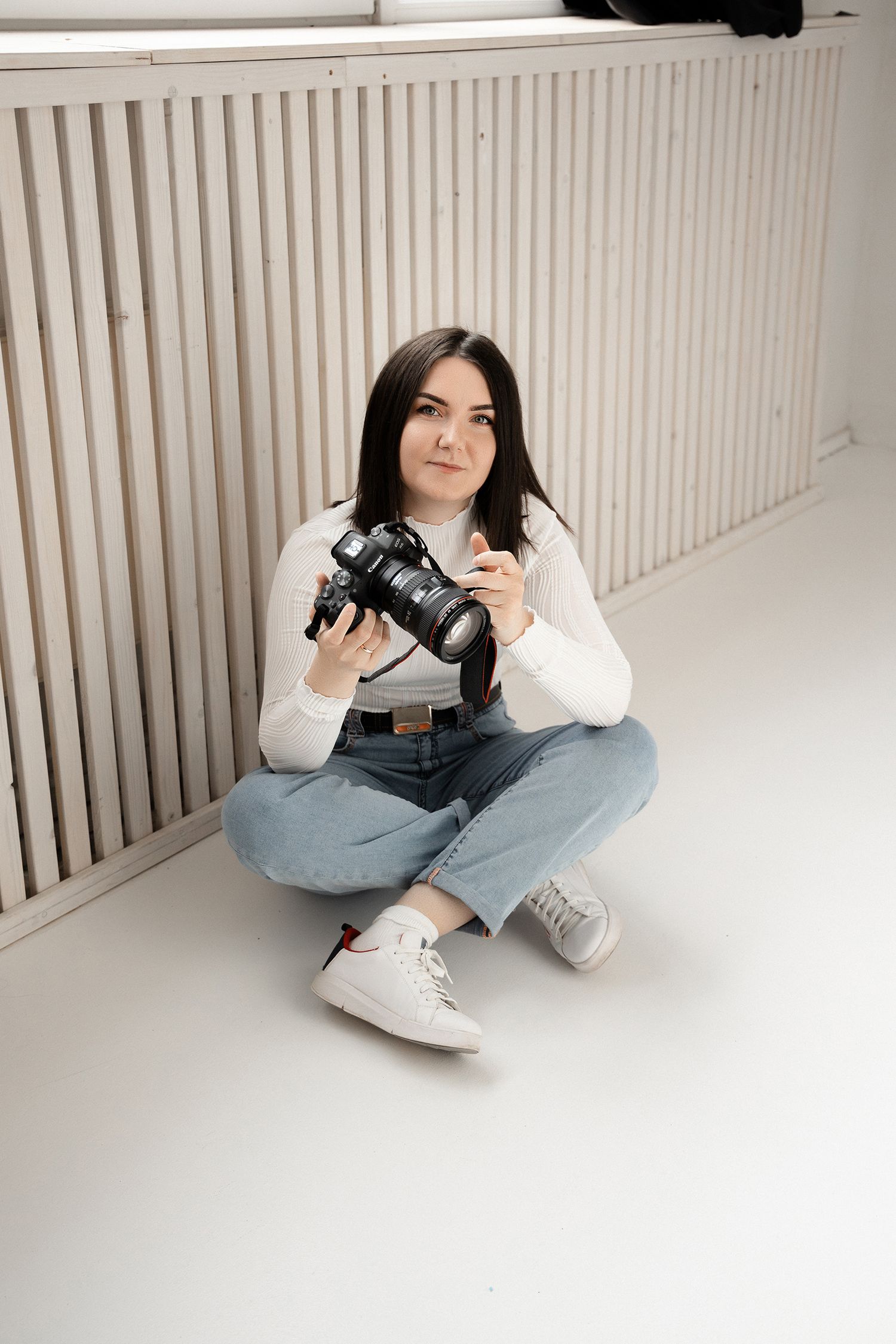 Vilnius portrait photographer Kateryna Tiupa (Katelavey) sits on the steps in jeans and a bomber jacket