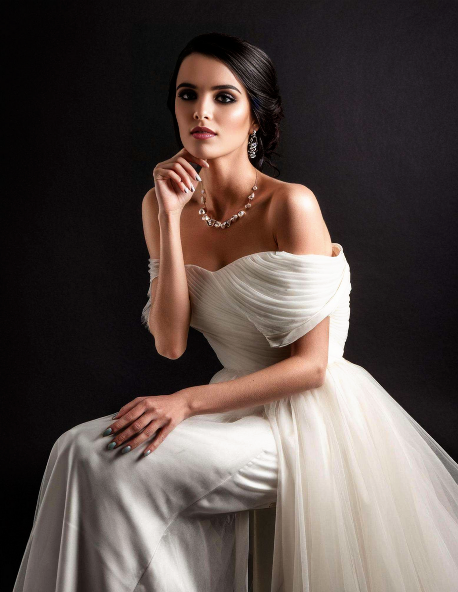 Classic bridal portrait featuring off-shoulder white gown and elegant jewelry.