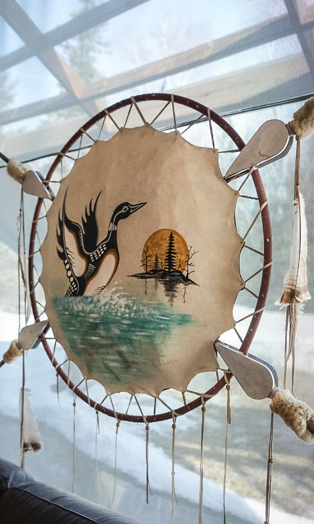 Native American-style artwork on circular drums displayed in a window installation.