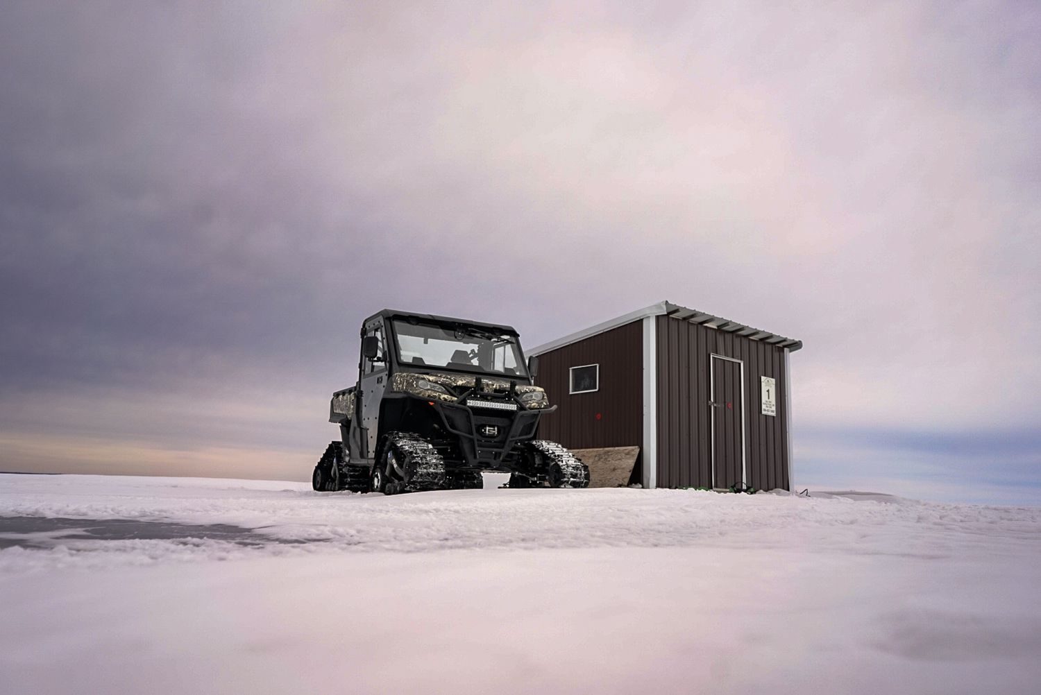 Snow-covered buildings on a remote winter landscape under cloudy skies.