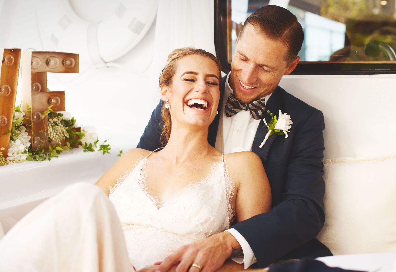 couple laughing on a boat after getting married in a navy suit