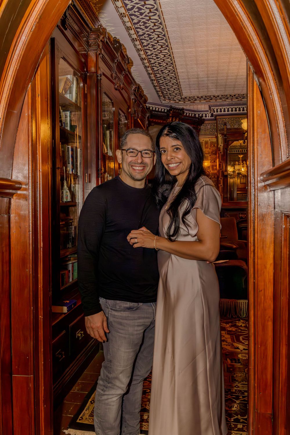People enjoying themselves in an elegant wood-paneled room with ornate arched doorways and warm lighting.